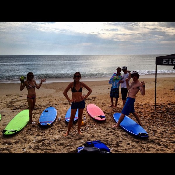 Five people on beach with surfboards