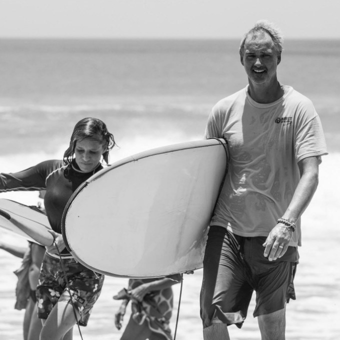 Black and white image of man and woman with surfboards