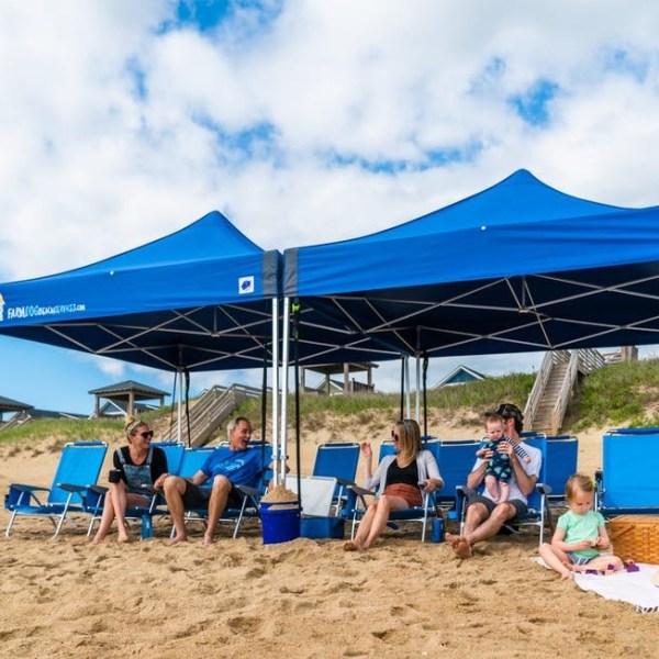 a group of people on a beach holding a blue umbrella