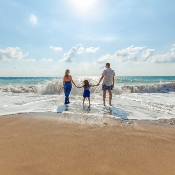 a family walking across a beach next to the ocean
