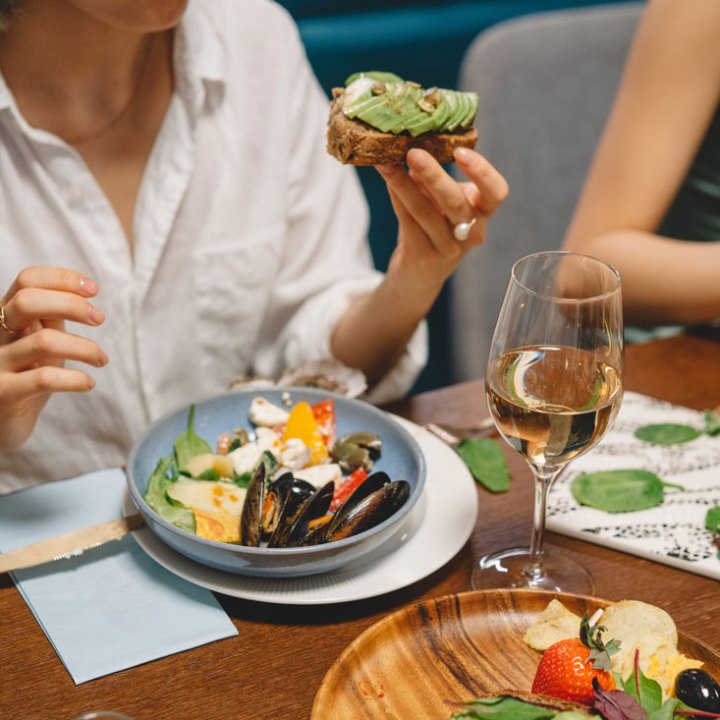 a woman sitting at a table with a plate of seafood and wine
