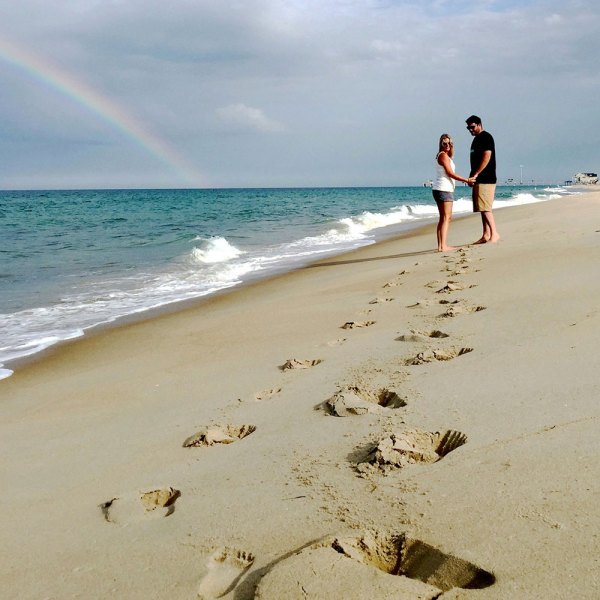 a couple standing on top of a sandy beach