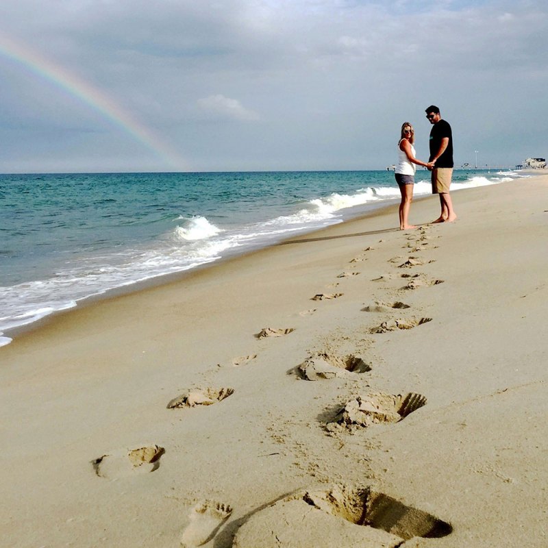 a couple standing on top of a sandy beach