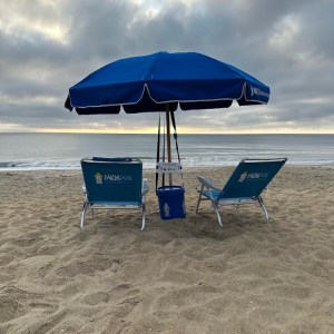 a couple of lawn chairs sitting on top of a sandy beach