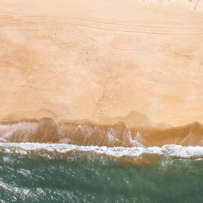 Aerial view of waves crashing on a sandy beach.
